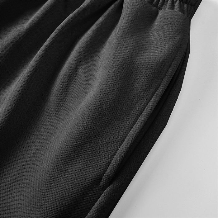 Close-up of the black sweatpants leg showing smooth fabric, folds, and a finished side seam