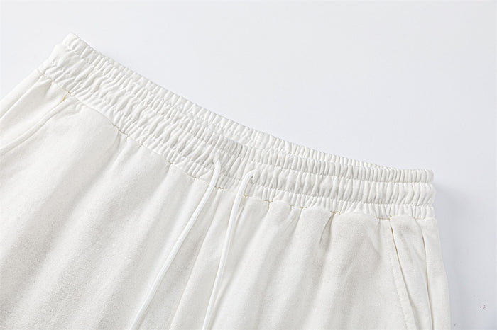 Close-up of the white sweatpants’ gathered elastic waistband and front drawstring