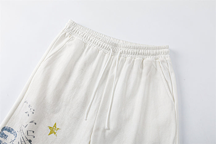 Close-up of white sweatpants showing the elastic waistband, drawstring, and partial music graphic