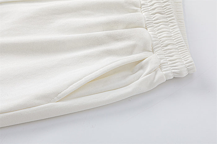 Close-up of the white sweatpants’ side seam and angled side pocket opening