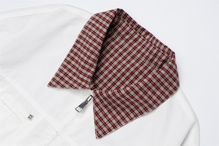 Close-up of the burgundy plaid collar on a white jacket with the front zipper below