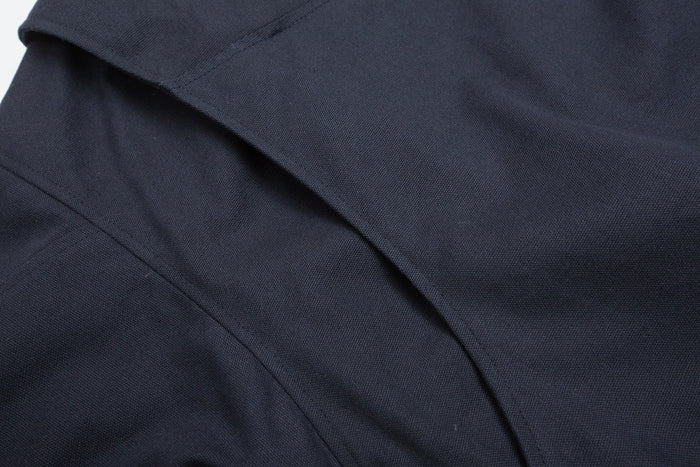 Close-up of the navy jacket’s textured fabric and overlapping stitched panel details
