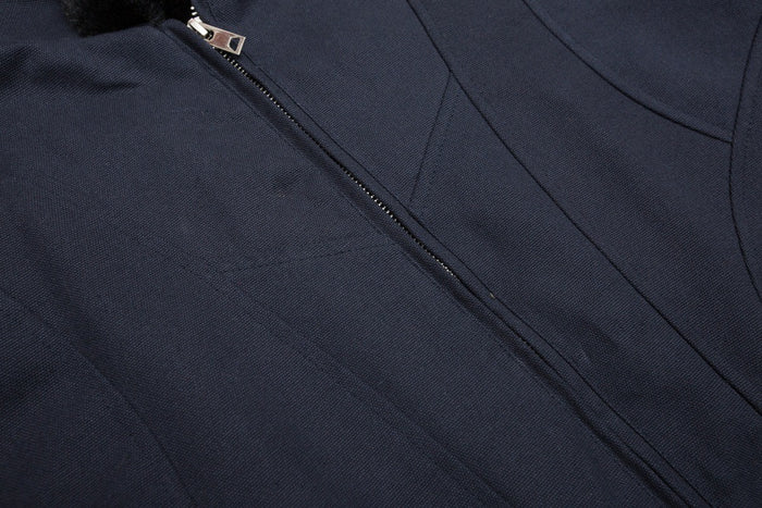 Detailed view of the navy jacket’s front zipper and curved stitched panel seams