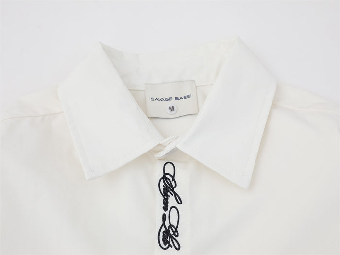 Close-up of white shirt collar and top placket with script embroidery and brand label