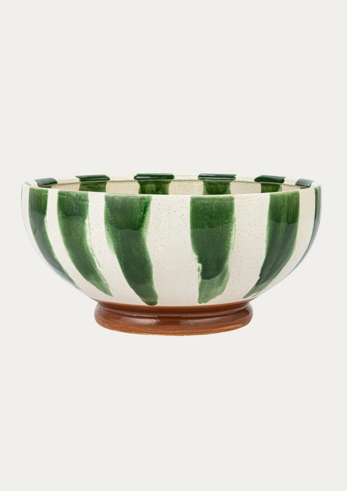 A large ceramic bowl in white with painted vertical green stripes and brown footed base.