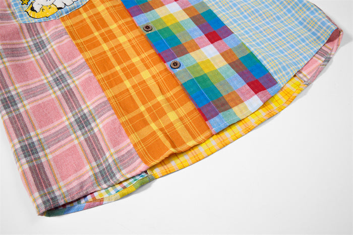 Close-up of the shirt hem showing pink, orange, blue, and yellow patchwork plaid panels with front buttons