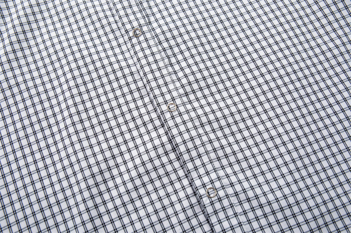 Close-up of the white plaid shirt front placket with metallic buttons and intersecting dark grid pattern