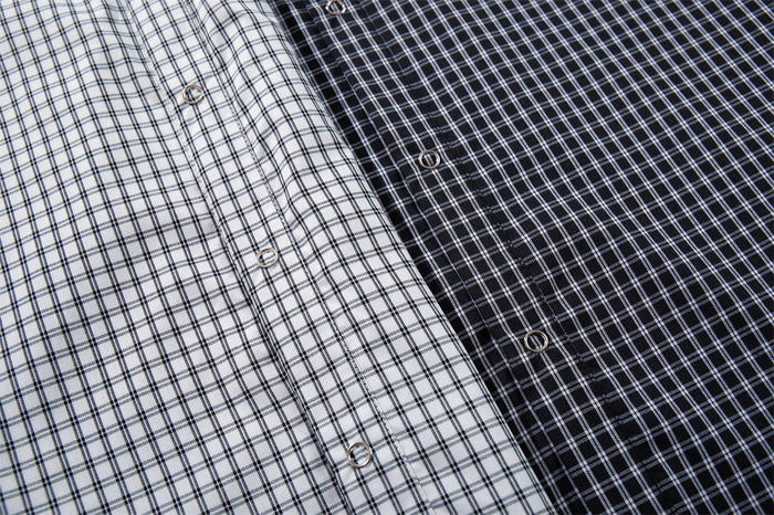 Close-up comparing white and black plaid shirt fronts with metallic buttons and matching grid patterns