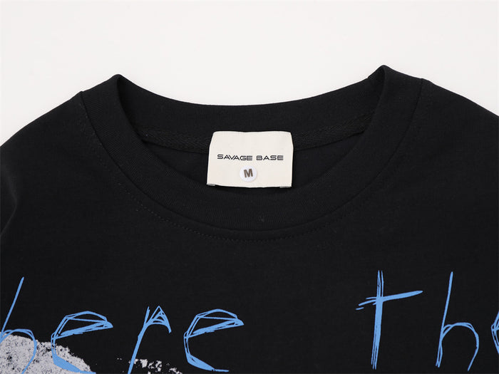 Close-up of the black T-shirt crew neckline, sewn label, and partial blue graphic lettering