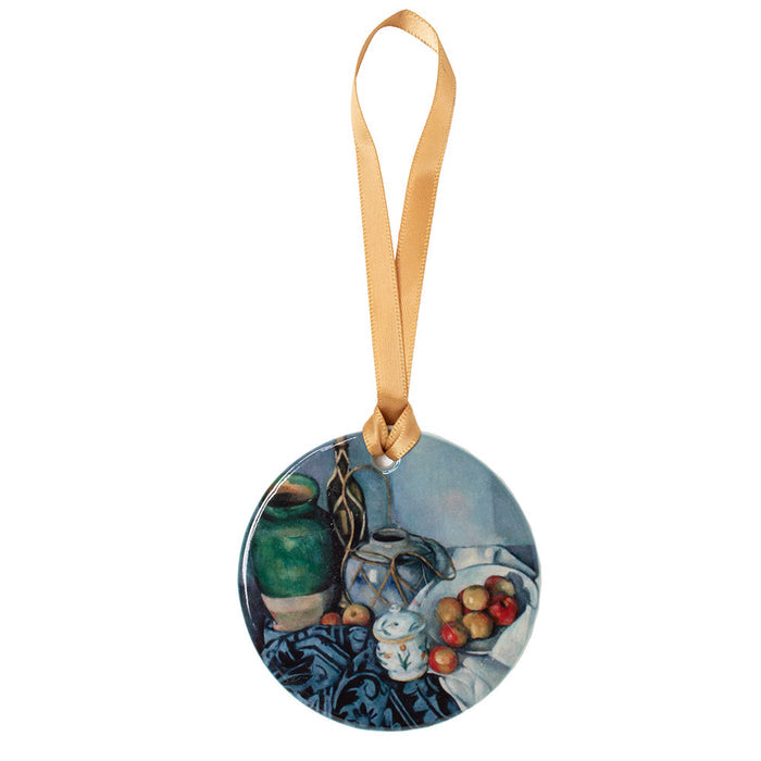 A porcelain ornament featuring a reproduction of Paul Cézanne's Still Life with Apples, depicting various objects on a table with a focus on apples, a green vase, and other items.