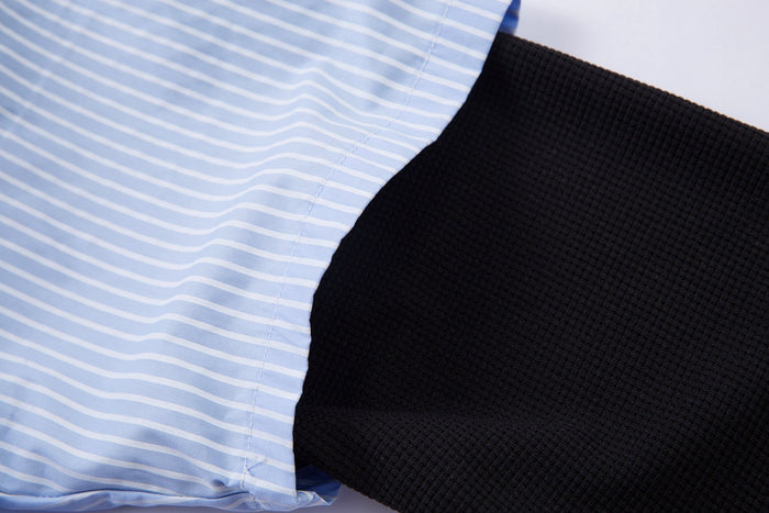 Close-up of blue pinstripe shirt fabric layered over black textured sleeve