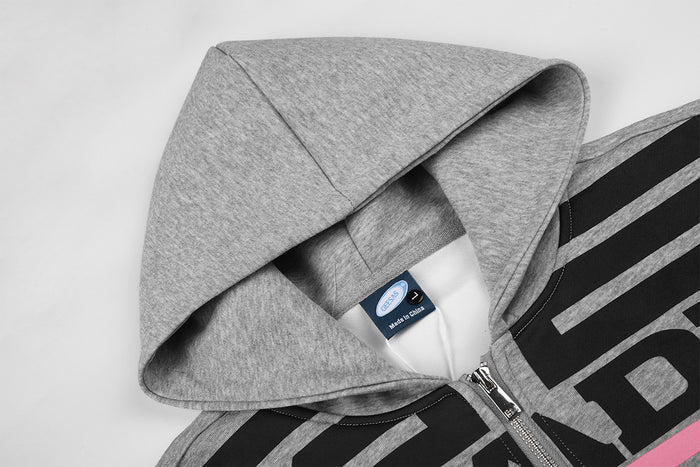 Close-up of the gray hoodie hood, inner label, zipper, and bold black and pink front graphic