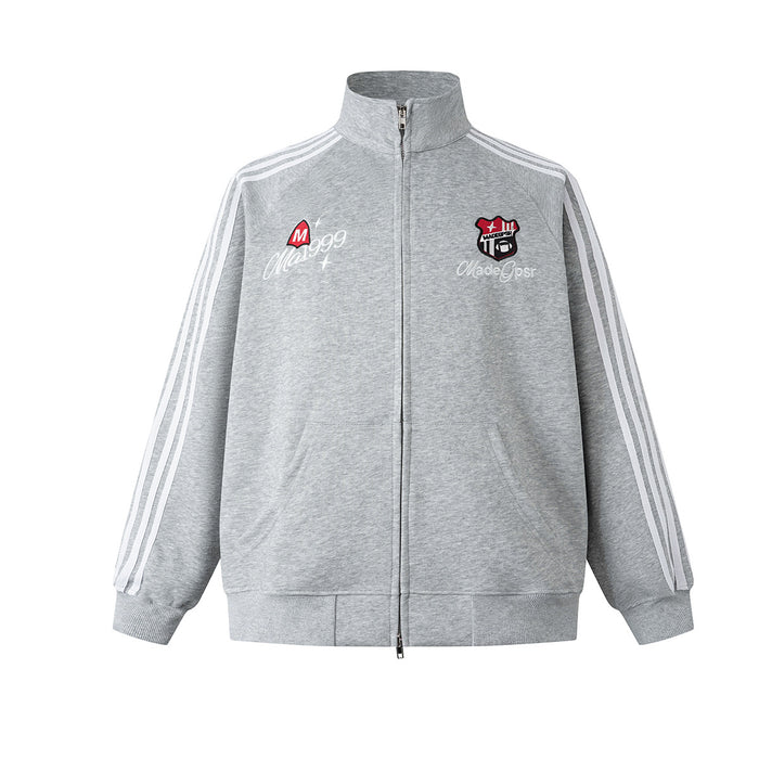 Front view of gray zip-up track jacket with stand collar, white sleeve stripes, and embroidered chest badges