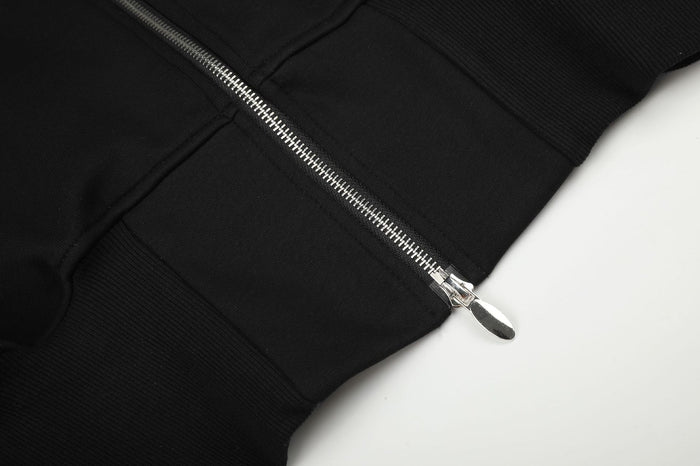 Close-up of the silver front zipper and pull tab meeting the black ribbed hem