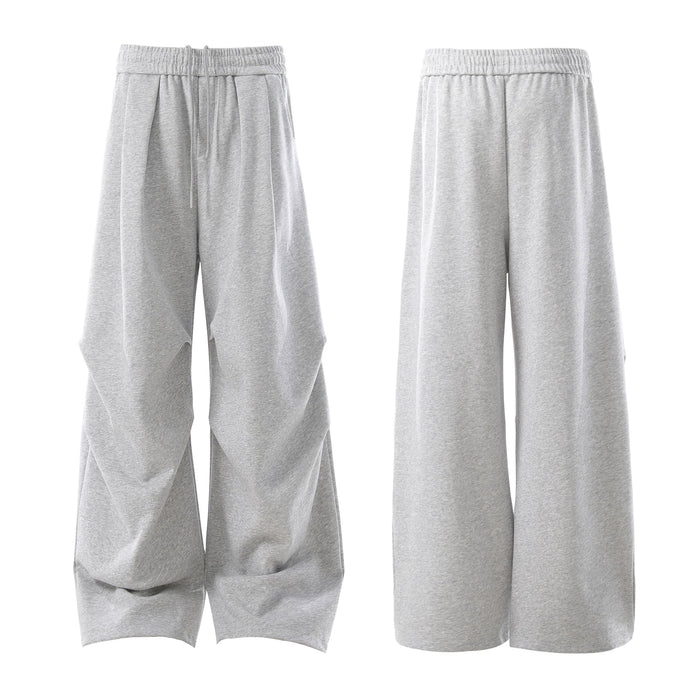 Side view of light gray wide-leg sweatpants showing pleated volume and loose fit