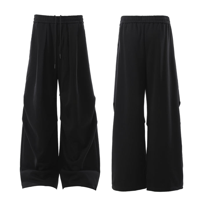 Side view of black wide-leg sweatpants showing oversized drape and sculpted pleats