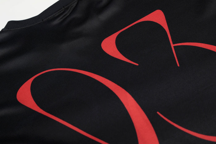 Black mesh jersey with bold red abstract portrait graphics and a ribbed crew neckline, shown in close-up
