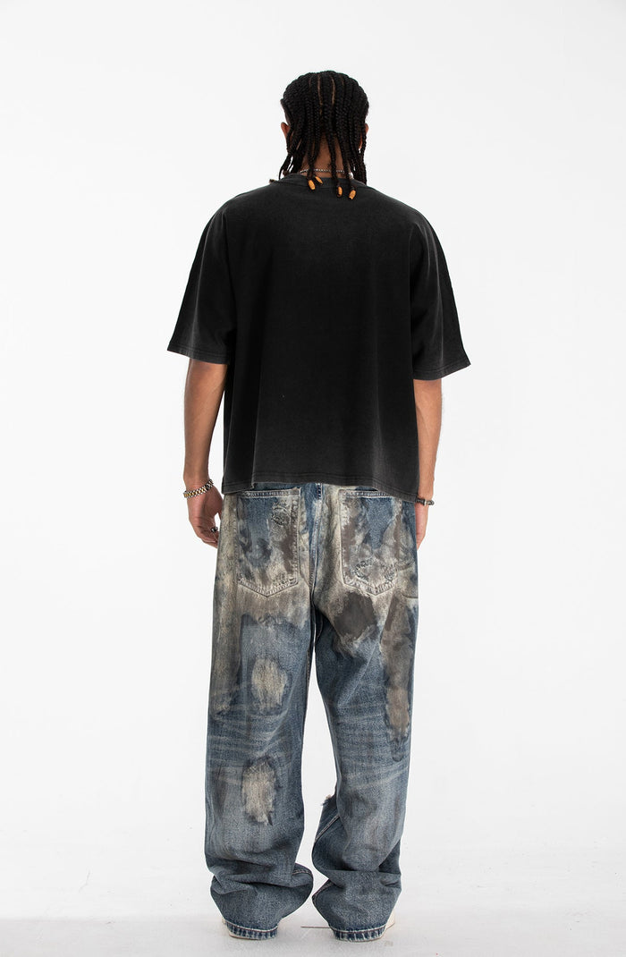 Black oversized gothic graphic tee styled with loose faded jeans on a model photographed from the back