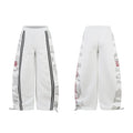 Front and back view of light grey wide-leg sweatpants with white camo side panels, black stripes and red script lettering
