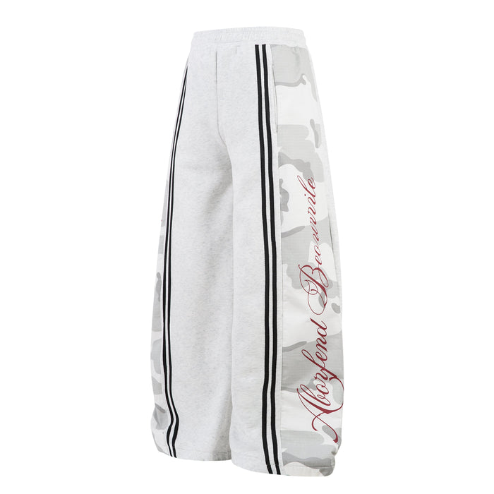 Three-quarter side view of light gray wide-leg sweatpants with camo side panel and red script detail