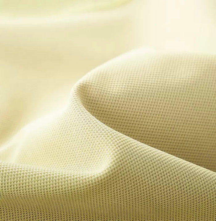 Close-up of beige textured cotton T-shirt fabric with smooth color-block panel detail and soft streetwear feel