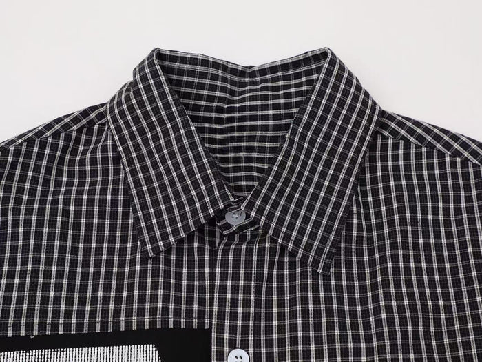 Black and white plaid button-up shirt with a spread collar and relaxed streetwear style