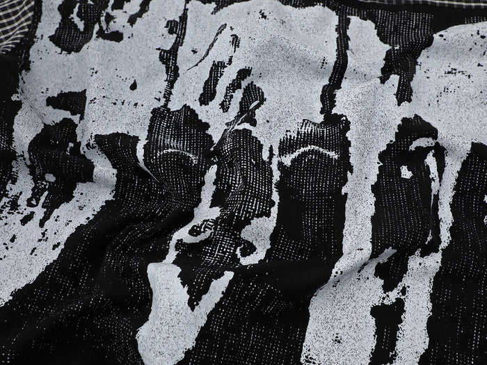 Black and white plaid shirt fabric with abstract graphic print and textured streetwear pattern close-up