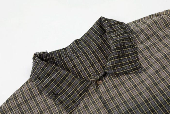 Distressed black and yellow plaid shirt with raw edges, shown close up on a white background