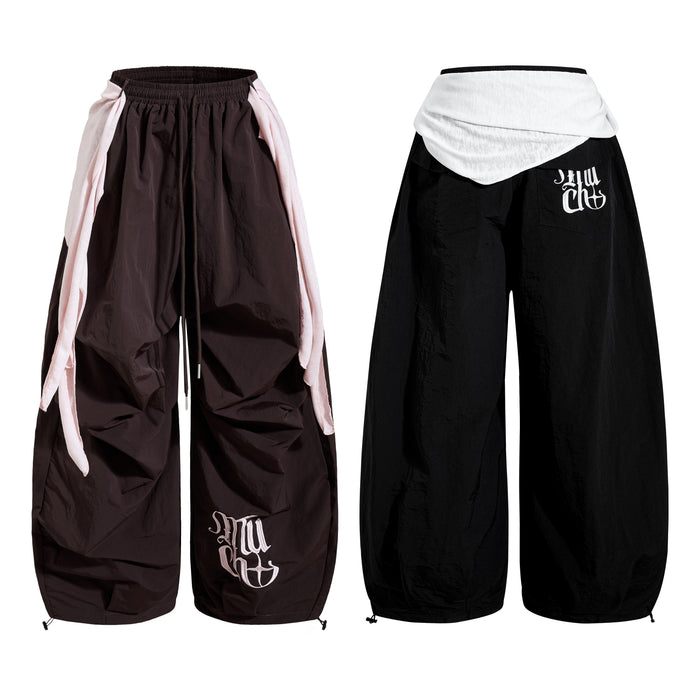Dark brown wide-leg nylon pants with pink draped side panels and gothic embroidered logo, front and back view