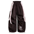 Front view of dark wide-leg nylon pants with pale layered side panels and white graphic