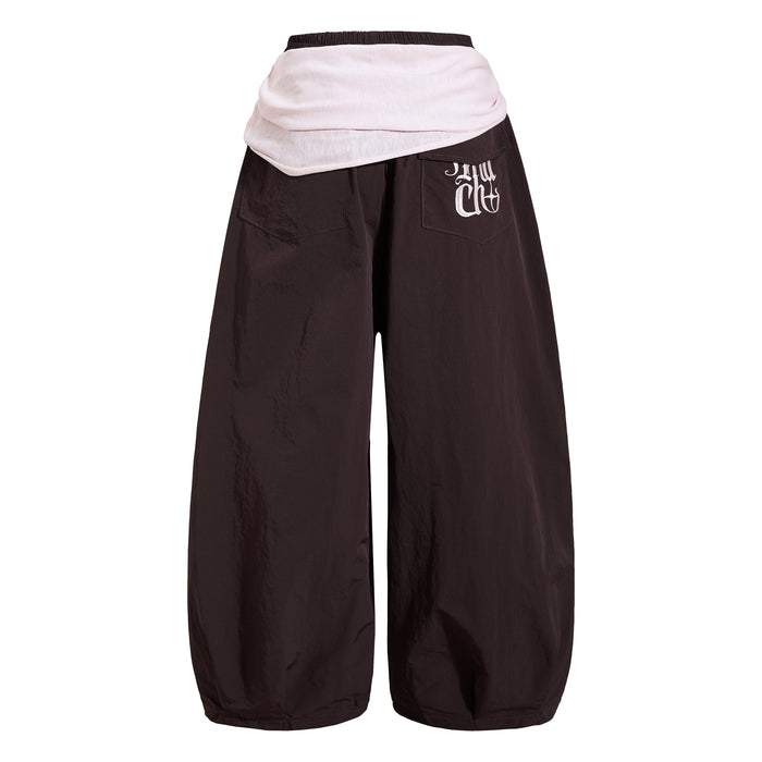 Back view of dark wide-leg nylon pants with pale layered waistband panel and rear pockets