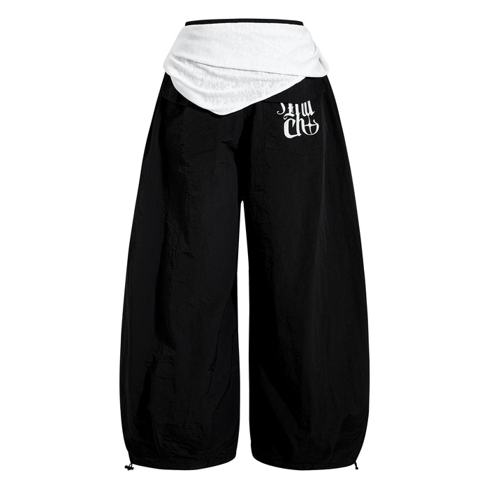 Back view of black wide-leg nylon pants with white layered waistband panel and rear pockets