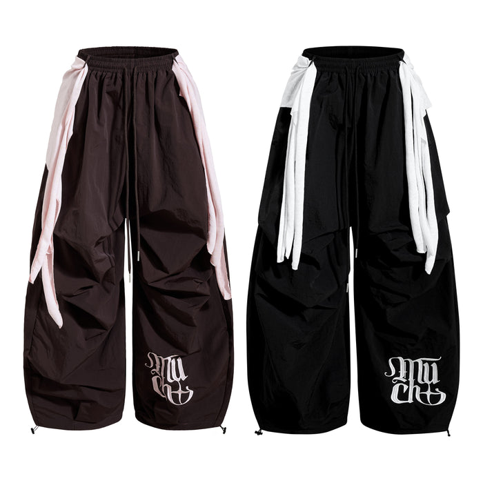 Side-by-side view of dark and black wide-leg nylon pants showing layered side panels