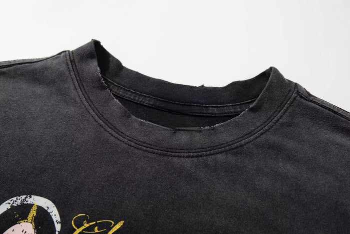 Close-up of a washed black graphic tee with distressed collar and street art style print in yellow and white