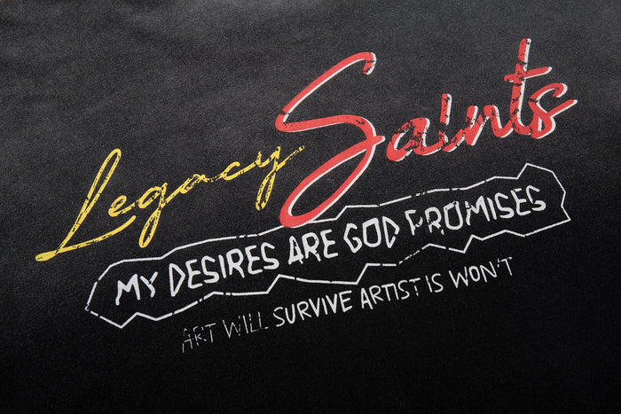 Washed black graphic tee with red Saints script, yellow Legacy text, and white quote print on the chest