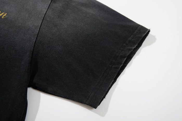 Black washed graphic tee sleeve with raw-cut hem and subtle street art print on soft cotton fabric