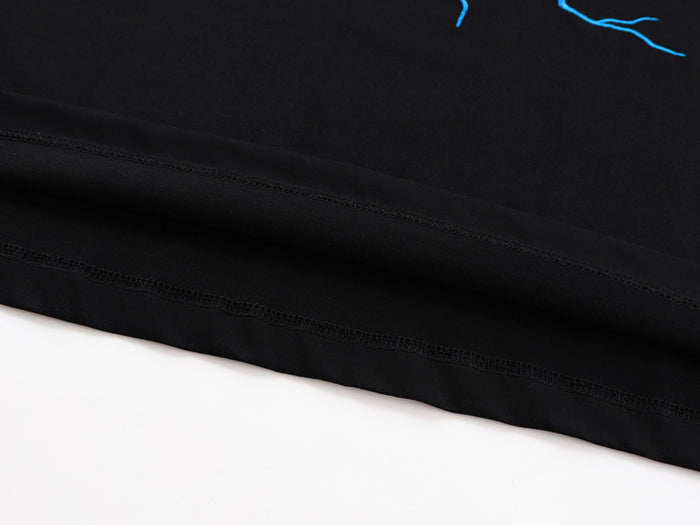 Black oversized graphic tee with blue lightning print and visible stitched hem on white background
