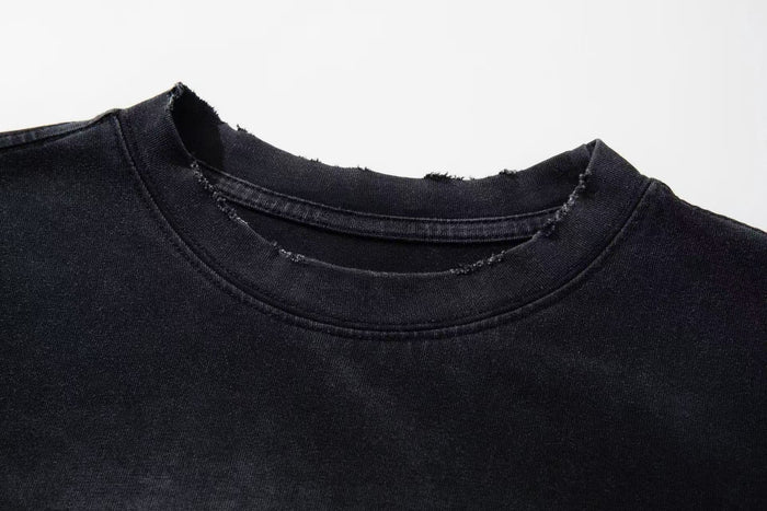 Black washed graphic tee with distressed raw-edge collar and vintage faded finish