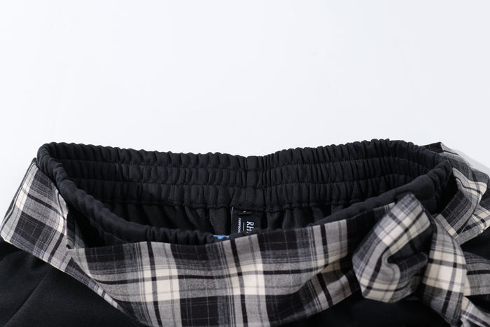 Close-up of black elastic waistband and black-white plaid tie belt on track pants