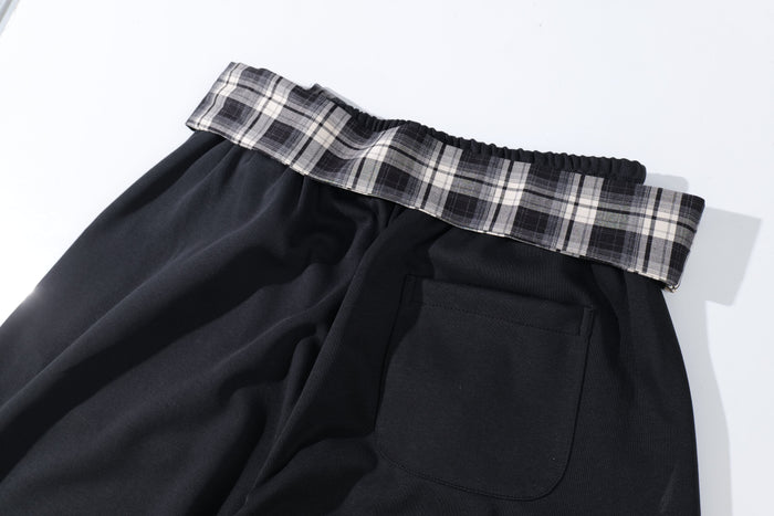 Close-up of plaid tie waistband, back pocket, and black fabric on the pants