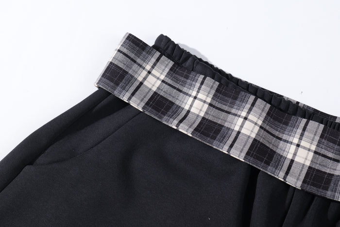 Close-up of plaid waistband and black fabric on the barrel track pants