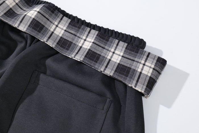 Close-up of plaid waistband and back patch pocket on black track pants