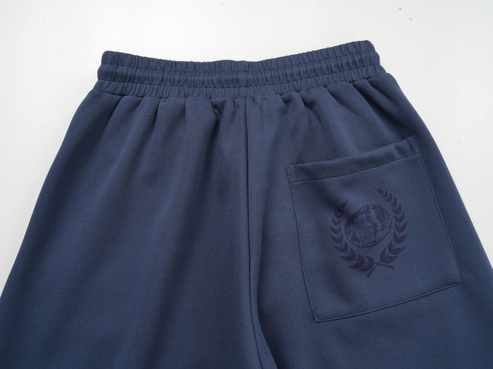 Close-up of the back pocket on navy sweatpants with faint globe laurel print