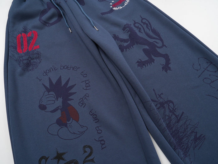 Diagonal view of navy sweatpants showing allover sketch graphics and front leg print