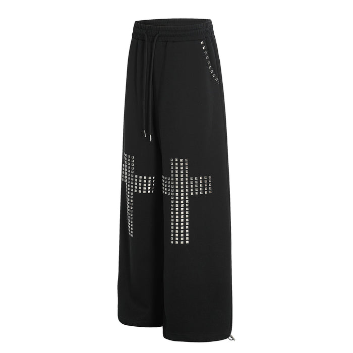 Black wide-leg sweatpants with silver studded cross details, angled front view
