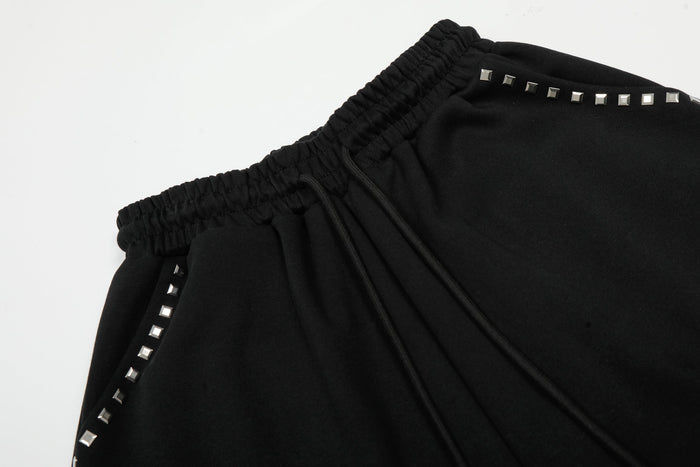 Close-up of black elastic waistband and side studded trim on wide-leg sweatpants