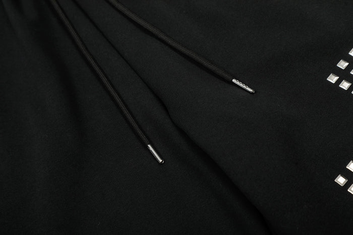 Close-up of drawstring tips and studded leg detail on black sweatpants