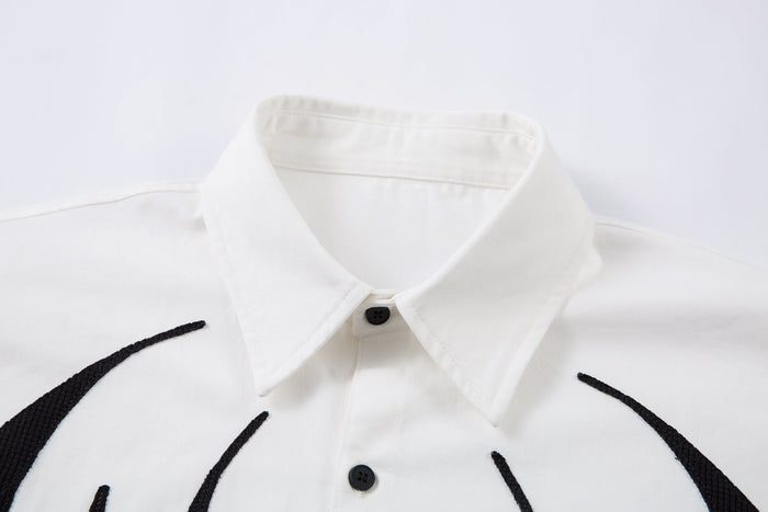 Close-up of white shirt collar and top buttons with black flame graphic at shoulders