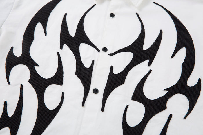 Close-up of white shirt front with black tribal flame graphic and buttons