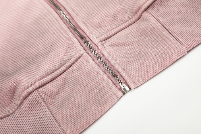 Close-up of the pink hoodie lower front with metal zipper, kangaroo pocket seams and ribbed waistband